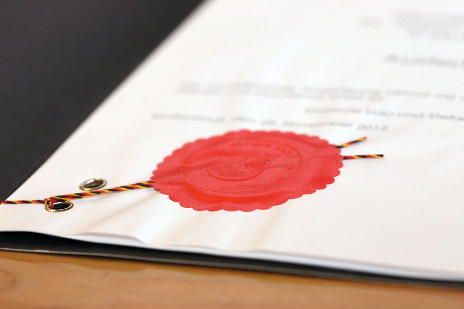 Notarkanzlei Alexandra Müller – Ein amtliches Dokument mit einem roten Wachssiegel, das mit einem schwarz-rot-goldenen Band befestigt ist.